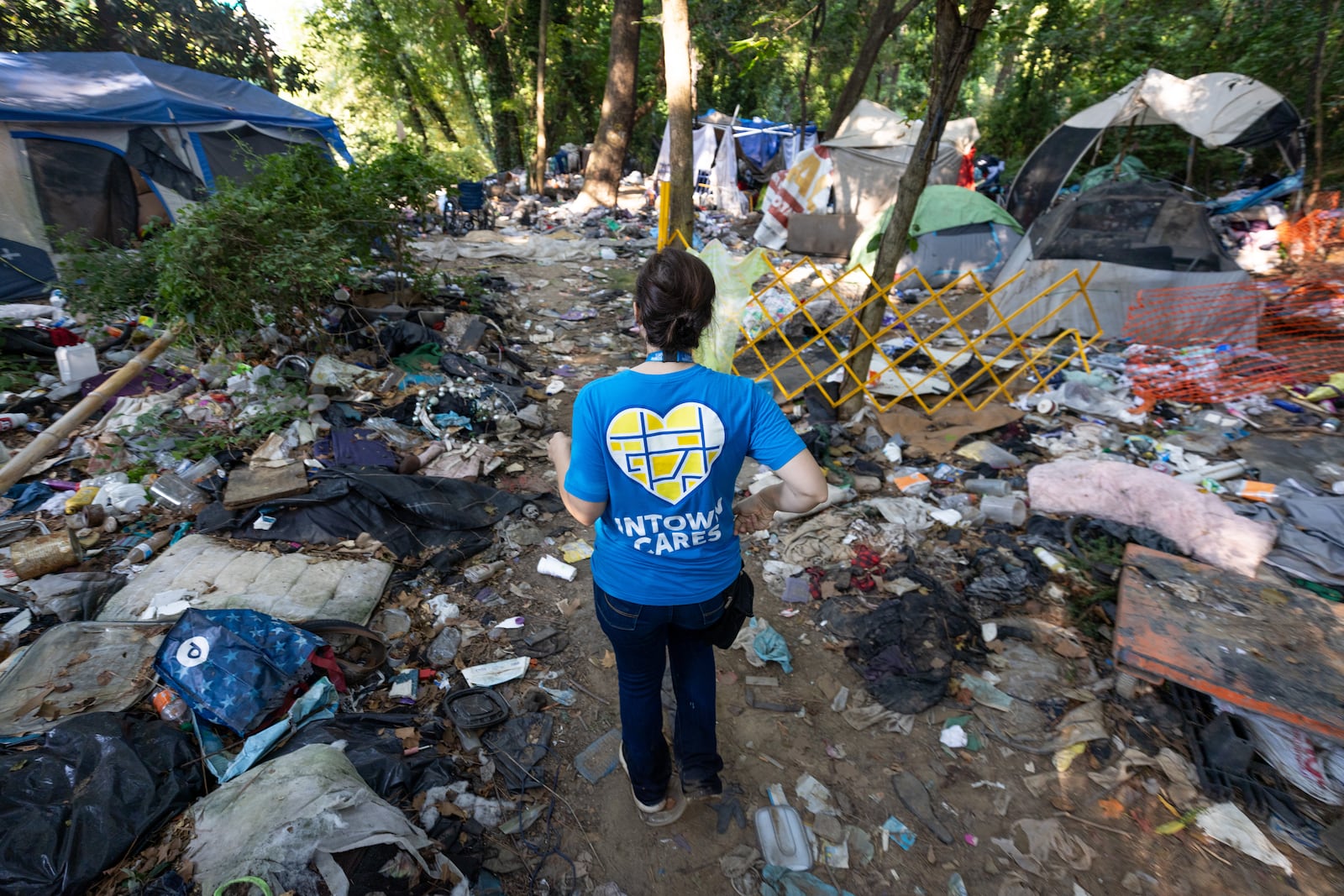 Intown Cares outreach representative Tracy Woodard moves through a homeless encampment Along the banks of Peachtree Creek, informing them of an upcoming free medical care opportunity Tuesday, August 22, 2023.  (Steve Schaefer/steve.schaefer@ajc.com)