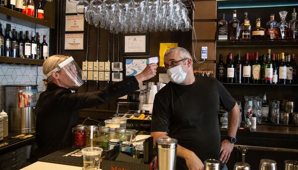 1920 Tavern Owner Jenna Aronowitz takes the temperature of bartender Shane Goode before the Roswell restaurant opens for sit down meals Monday, April 27, 2020. STEVE SCHAEFER / SPECIAL TO THE AJC