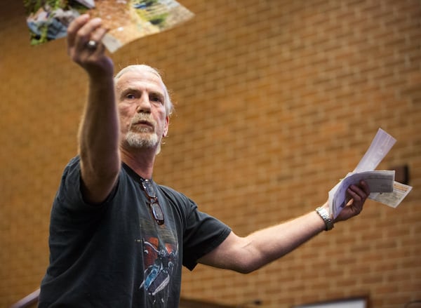 Todd Downing shows pictures of the trash he claims he has to clean up on his property near the MUST Ministries facility as the Marietta City Council considers Ministries’ request for a zoning variance to let it build a 130-bed homeless shelter. PHIL SKINNER