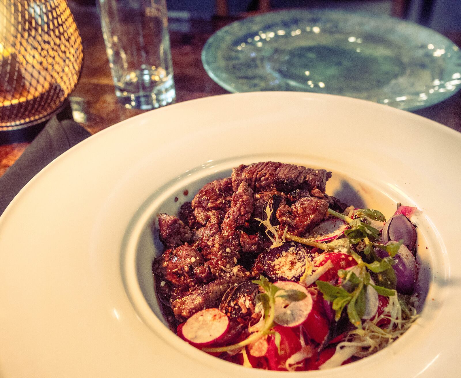 Shaking Beef 8-ounce filet mignon with frisée salad and marinated tomatoes. 
Courtesy of Girl Diver