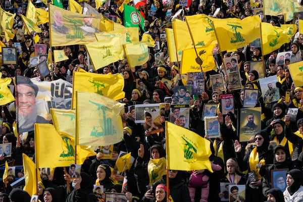 Mourners wave Hezbollah flags as a trailer carrying the coffins containing the bodies of Hassan Nasrallah and his cousin and successor Hashem Safieddine drives through the crowd at the beginning of a funeral procession in the Sports City Stadium in Beirut, Lebanon, Sunday, Feb. 23, 2025. (AP Photo/Hussein Malla)