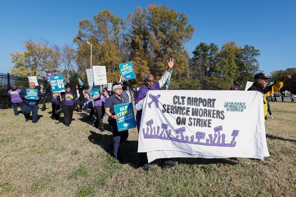 Airport workers wave signs as they march in front of the Charlotte Douglas International Airport in Charlotte, N.C., Monday, Nov. 25, 2024. (AP Photo/Nell Redmond)