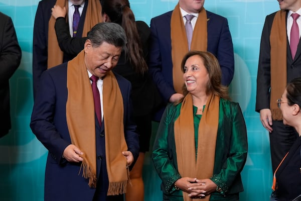 China's President Xi Jinping, left, speaks with Peru's President Dina Boluarte, right, as they and other APEC leaders gather for a family photograph at the APEC Summit in Lima, Peru on Saturday, Nov. 16, 2024. (AP Photo/Manuel Balce Ceneta)