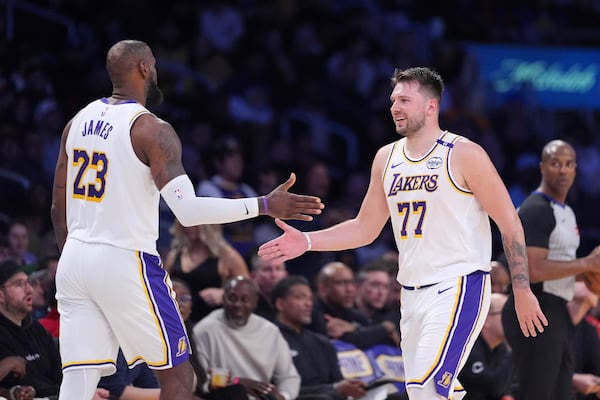 Los Angeles Lakers forward LeBron James, left, and guard Luka Doncic slap hands as Doncic comes out of the game and James comes in during the second half of an NBA basketball game against the Los Angeles Clippers, Sunday, March 2, 2025, in Los Angeles. (AP Photo/Mark J. Terrill)