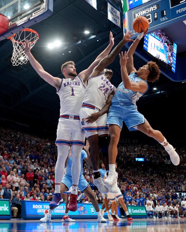 North Carolina guard Seth Trimble, left, shoots under pressure from Kansas center Hunter Dickinson (1) and forward KJ Adams Jr. (24) during the second half of an NCAA college basketball game Friday, Nov. 8, 2024, in Lawrence, Kan. Kansas won 92-89. (AP Photo/Charlie Riedel)