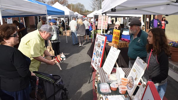 Joseph Costa, owner of Costa’s Pasta, and his granddaughter, Catherine Costa, 12, greet customers at Marietta Square Farmers Market on a recent Saturday. HYOSUB SHIN / HSHIN@AJC.COM