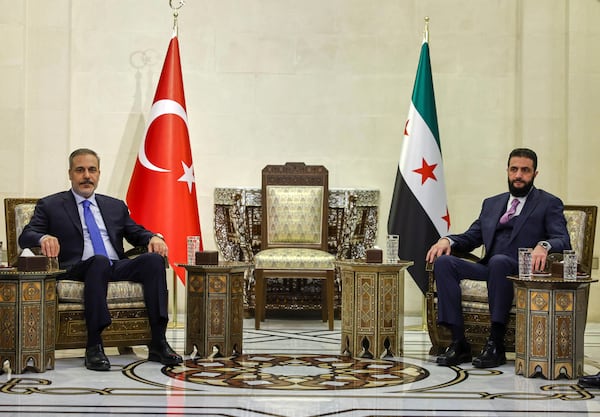 In this handout photo released by the Turkish Foreign Ministry press service, Turkish Foreign Minister Hakan Fidan, left, sits with Syria's interim president Ahmad Al-Sharaa, during their meeting in Damascus, Syria, Thursday, March 13, 2025. (Turkish Foreign Ministry press service via AP)