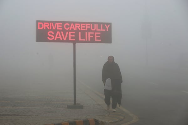 FILE - A man walks past a sign that reads "Drive carefully save life" in Peshawar, Pakistan, Jan. 23, 2024. (AP Photo/Muhammad Sajjad, File)