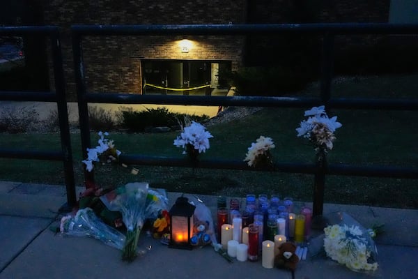 Flowers and candles are placed outside the Abundant Life Christian School Tuesday, Dec. 17, 2024 in Madison, Wis., following a shooting on Monday. (AP Photo/Nam Y. Huh)