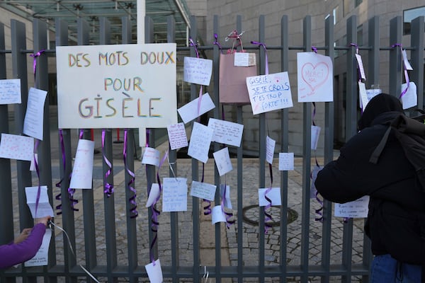 Activists attach nice words for Gisèle Pelicot, one reading "Gentle words for Gisele" on the fence of the Palace of Justice before a women's rights demonstration, Saturday, Dec. 14, 2024 in Avignon, southern France, where the trial of dozens of men accused of raping Gisèle Pelicot while she was drugged and rendered unconscious by her husband is taking place. (AP Photo/Aurelien Morissard)