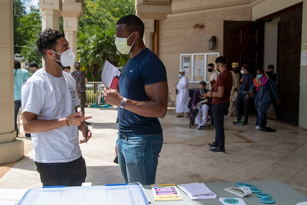 Georgia Muslim Voter Project Community Organizer Salik Sohani, left, speaks with Ben Coulibaly about voter registration following prayer outside of the Al-Farooq Masjid in downtown Atlanta in August 2021. (Alyssa Pointer/Atlanta Journal Constitution)