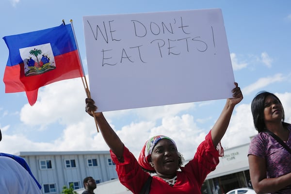 FILE - Wilda Brooks of West Palm Beach, Fla., holds up a sign reading "We don't eat pets," during a rally by members of South Florida's Haitian-American community to condemn hate speech and misinformation about Haitian immigrants, Sunday, Sept. 22, 2024, in North Miami, Fla. (AP Photo/Rebecca Blackwell, File)