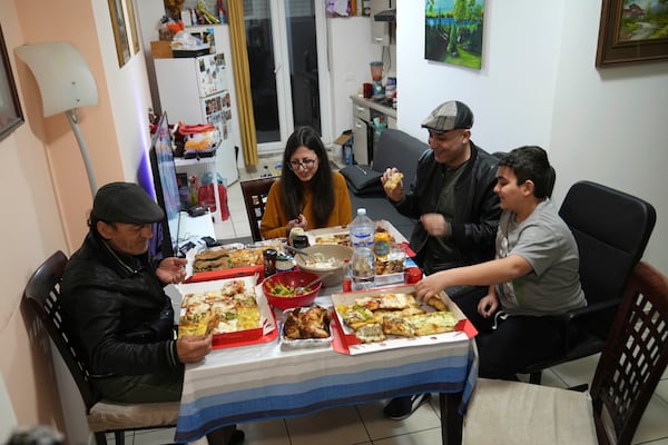 For left, Riad Zaheda, father of Hasan, Nour Essa, Hasan's wife, Hasan Zaheda and their son Riad eat during the iftar – during the Ramadan the meal breaking the day's fast – in their house in Rome, Sunday, March 2, 2025. (AP Photo/Alessandra Tarantino)