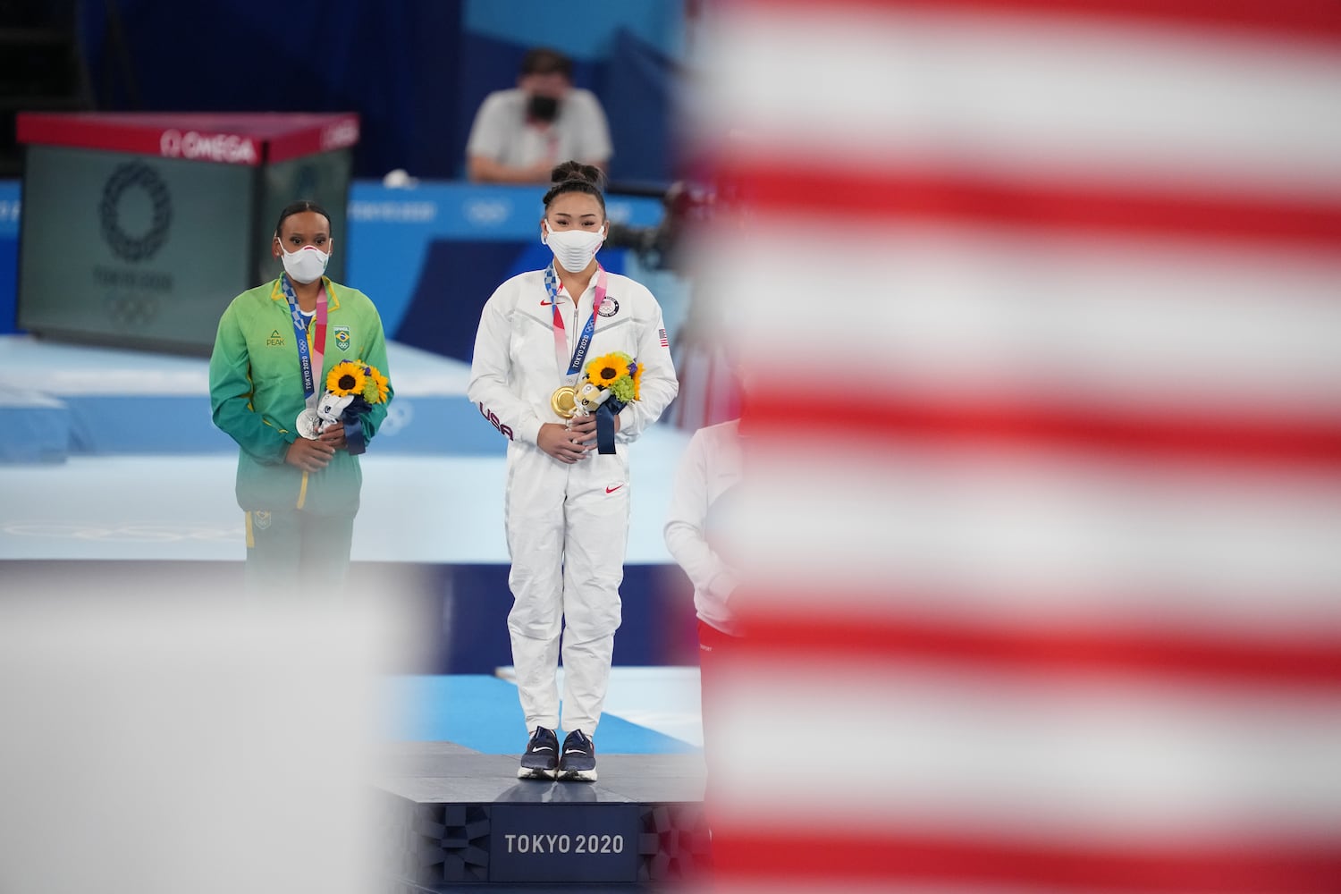 Sunisa Lee of the United States, center, with her gold medal and Rebeca Andrade of Brazil, left, with her silver medal, stand during the medal ceremony following the women's all-around gymnastics competition at the postponed 2020 Tokyo Olympics in Tokyo on Thursday, July 29, 2021. (Chang W. Lee/The New York Times)