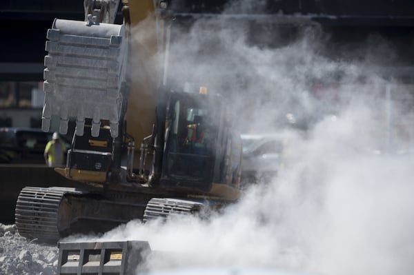 A shovel moving debris at the collapse site throws a cloud of dust into the air Sunday near Piedmont Road. (DAVID BARNES / DAVID.BARNES@AJC.COM)