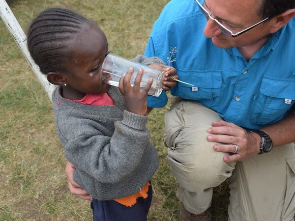 Bill Coble gives a little girl a drink of pure drinking water cleaned by the UZima water filter. The filter costs $40 to manufacture and deliver to families in Kenya who wouldn’t otherwise have access to clean drinking water. CONTRIBUTED