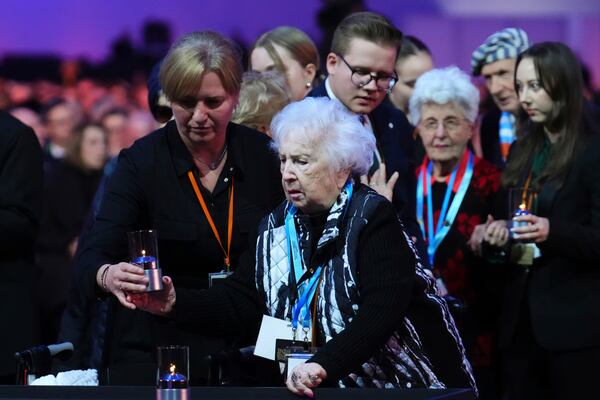 Canadian Holocaust survivor Miriam Ziegler, centre right, receives assistance as she places a candle during the Commemoration Ceremony of the 80th Anniversary of the Liberation of Auschwitz, in Oswiecim, Poland, Monday, Jan. 27, 2025. (Sean Kilpatrick/The Canadian Press via AP)