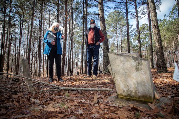 Johns Creek's Historical Society co-founder Joan Compton and board member Kirk Canaday look over a headstone at Macedonia African Methodist Church Cemetery. STEVE SCHAEFER for the AJC