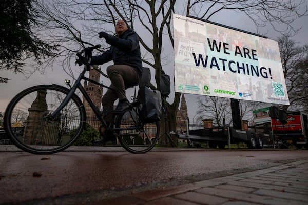 Activists put up a billboard outside the International Court of Justice, in The Hague, Netherlands, as it opens hearings into what countries worldwide are legally required to do to combat climate change and help vulnerable nations fight its devastating impact, Monday, Dec. 2, 2024. (AP Photo/Peter Dejong)