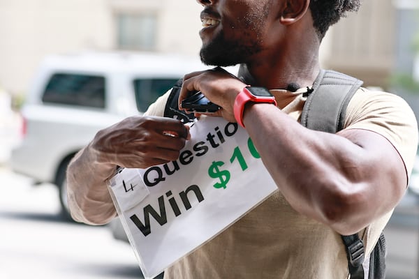 TikTok star Leon Ondieki pins a sign to his backpack before starting his trivia game on Friday, July 22, 2022. (Natrice Miller/natrice.miller@ajc.com)