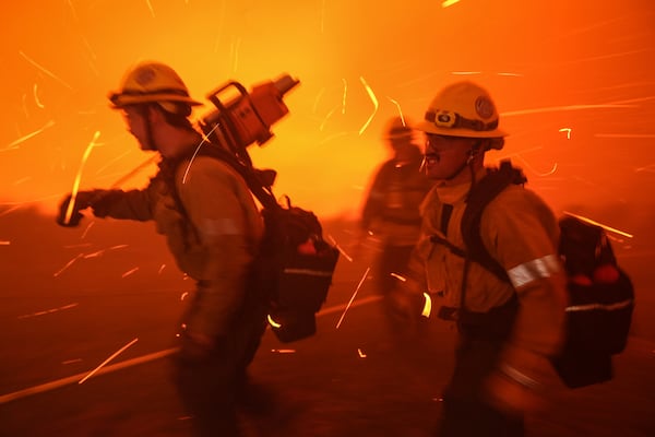 Firefighters are pushed back by gusty winds while removing fuel around the faculty and staff residences at Pepperdine University as the Franklin Fire approaches in Malibu, Calif., Tuesday, Dec. 10, 2024. (AP Photo/Jae C. Hong)