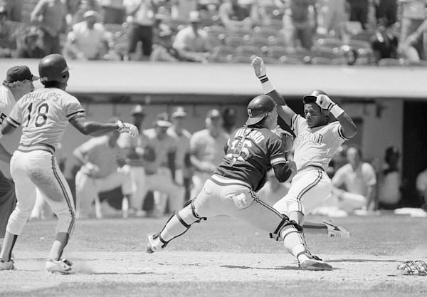 FILE - Oakland Athletics' Rickey Henderson, right, slides home safely past Cleveland Indians catcher Jerry Willard to score from third base on a hit by Davey Lopes during the seventh inning of a baseball game in Oakland, Calif., June 14, 1984. (AP Photo/Jeff Reinking, File)