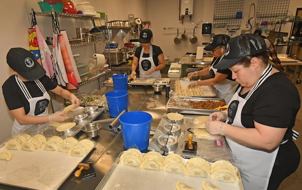 Workers fill, press and label empanadas in the kitchen of Belén de la Cruz Empanadas & Pastries. Along with traditional fillings, the company caters to the adventurous palates of Americans with nontraditional fillings like cheesy beef, butternut squash or caprese. (Chris Hunt for The Atlanta Journal-Constitution)