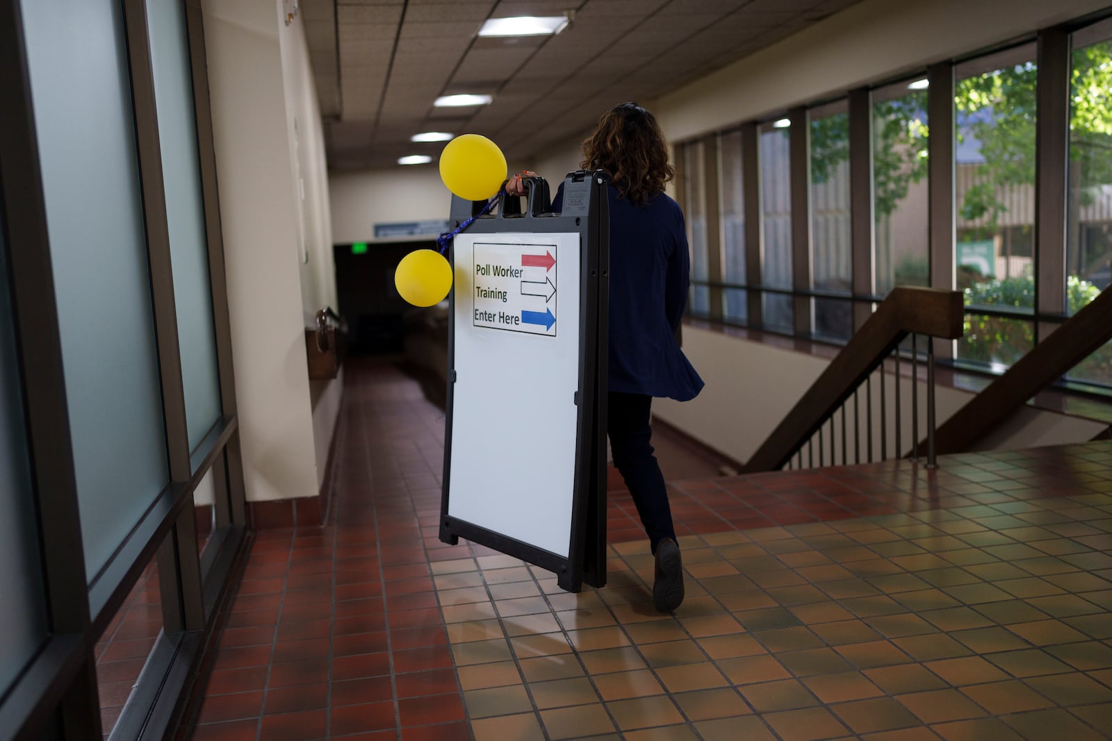 Wendy Steiner, office assistant at the Washoe County Registrar of Voters office, carries a sign for poll worker training Saturday, Sept. 21, 2024, in Reno, Nev. (AP Photo/John Locher)