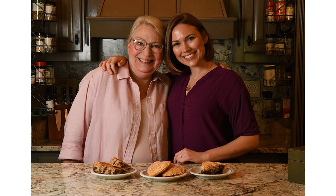 Ellen Wilson and her daughter Leah Parris, owner of Flour + Time vegan bakery, pose in the kitchen of Wilson's Forsyth home. The mother and daughter show some of Parris' favorite family recipes that have been turned into vegan treats: (from left) Miss Ellen’s Lunchbox Bars, Strawberry Turnovers and Mrs. Fox’s Shoofly Pie. (Styling by Leah Parris / Chris Hunt for the AJC)