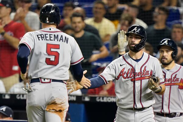 Atlanta Braves' Freddie Freeman (5) is congratulated by Dansby Swanson after Freeman scored on a single by Austin Riley during the fourth inning of a baseball game against the Miami Marlins, Wednesday, Aug. 18, 2021, in Miami. (AP Photo/Wilfredo Lee)