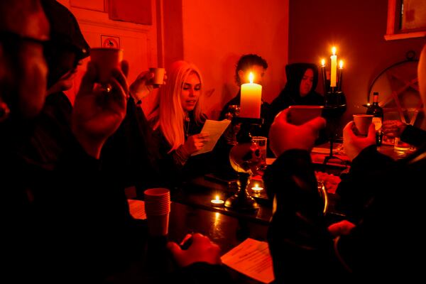 Members of The Temple of Satan: Satanists and Luciferians of Chile, drink wine at the start of a monthly ceremony in Santiago, Friday, Sept. 27, 2024. (AP Photo/Esteban Felix)