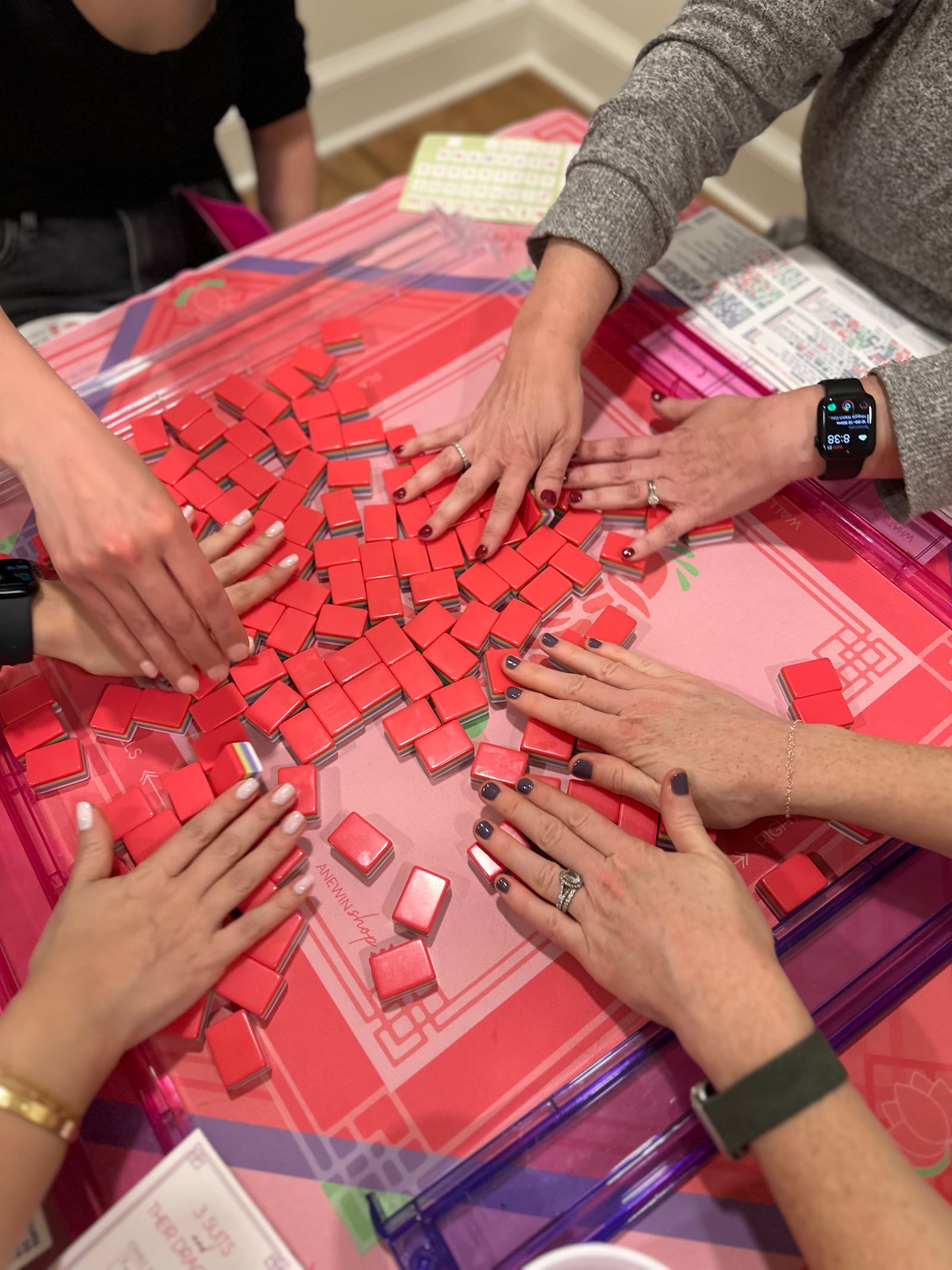 Mahjong gets its name from the clacking tiles, particularly noticeable when shuffling them, as players are doing here.
(Courtesy of Let's Rack and Roll)