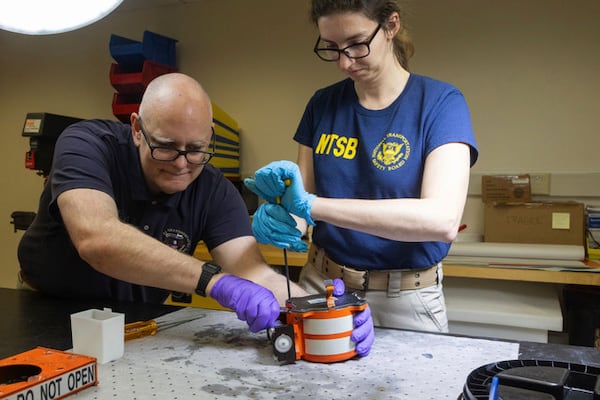 National Transportation Safety Board (NTSB) investigators examine cockpit voice recorder and flight data recorder recovered from the American Airlines passenger jet that crashed with an Army helicopter Wednesday night near Washington, D.C, Thursday, Jan.30, 2024. (NTSB via AP)