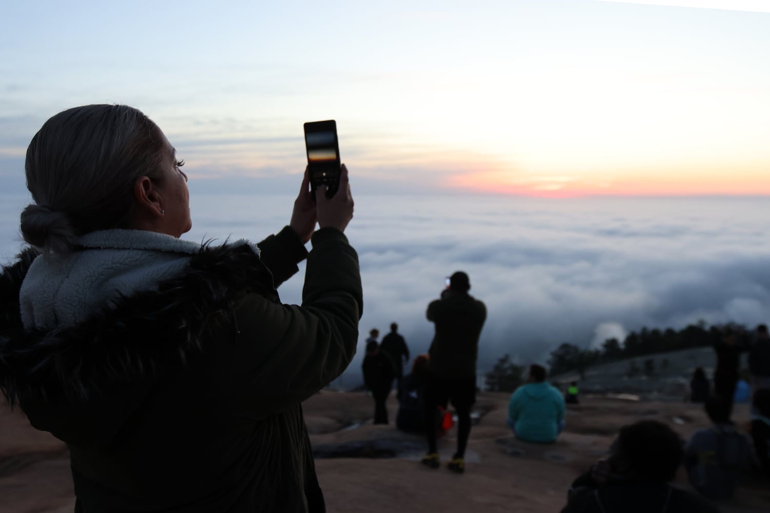 Sandra Hilario from Mableton, Ga, takes a photo as the sun rises during the 76th annual Easter Sunrise Service on Sunday, April 17, 2022. Miguel Martinez/miguel.martinezjimenez@ajc.com