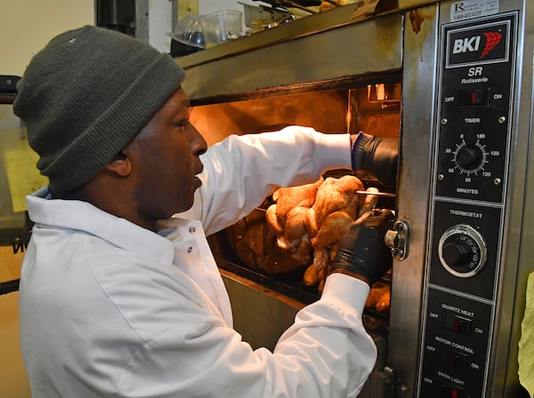 Diamond Mardell gets the whole chicken roasters going in the morning at Shield's Meat Market. Chris Hunt for The Atlanta Journal-Constitution