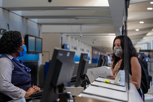 Casa Alterna volunteer Yehimi Cambrón speaks with an American Airlines customer service representative in order to change the flight of an immigrant at Atlanta's Hartsfield-Jackson International Airport, Thursday, Aug. 19, 2021. (Alyssa Pointer/Atlanta Journal Constitution)