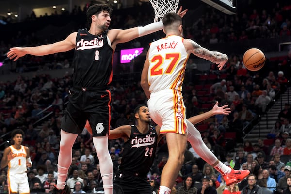 Atlanta Hawks guard Vit Krejci, right, passes the ball on Portland Trail Blazers forward Deni Avdija, left, as forward Kris Murray, center, defends during the first half of an NBA basketball game in Portland, Ore., Sunday, Nov. 17, 2024. (AP Photo/Steve Dykes)