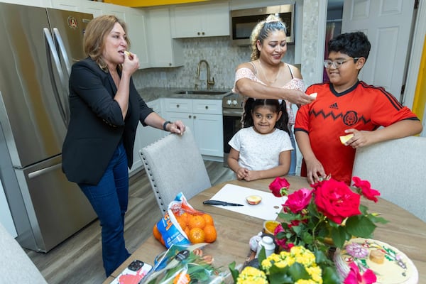 Allison Hill (left) shares an apple with Lucero Liborio and her two children Gabriella Velazquez and Antonio Velazquez in their southwest Atlanta home.   PHIL SKINNER FOR THE ATLANTA JOURNAL-CONSTITUTION