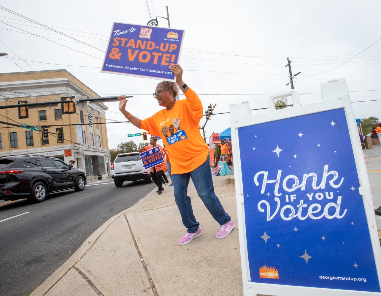 The last day of early voting in Georgia takes place at Metropolitan Library in South Fulton County; across the street several non-profit, non-partisan groups, including Connie Patrick, a volunteers with Georgia Stand Up, dances and cheers street side to encourage people to vote Friday, November 1, 2024.  The polling location had a steady stream of voters throughout the day.  (Jenni Girtman for The Atlanta Journal-Constitution)