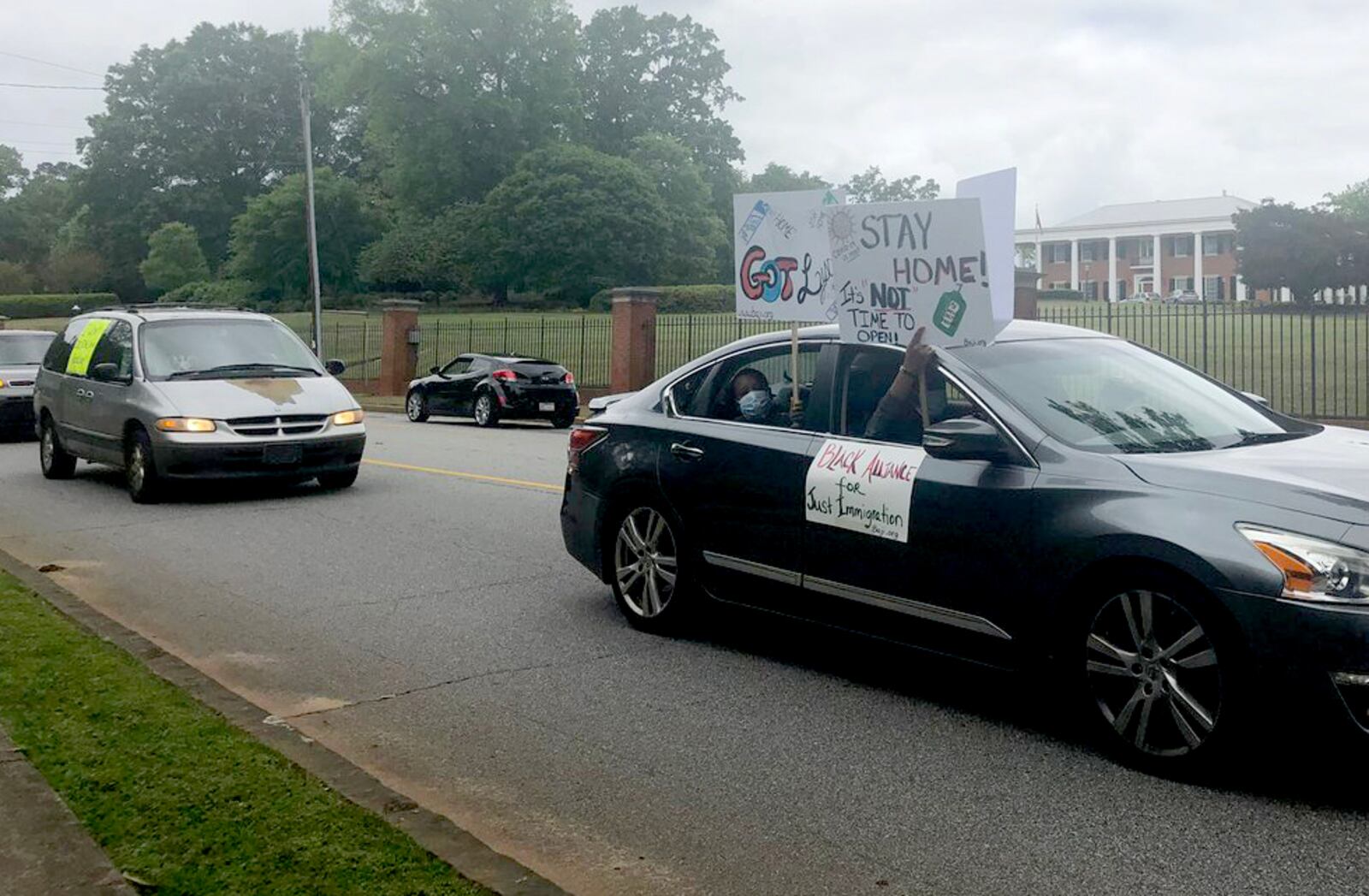 Protesters drive past the Governor's Mansion carrying signs and honking horns Friday. (Photo: Greg Bluestein/AJC)