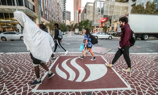 Students and other pedestrians intermingle as they cross the crosswalk at the intersection of Piedmont Avenue and John Wesley Dobbs Avenue at Georgia State University's Atlanta campus on Monday, Oct. 30, 2023. (John Spink / John.Spink@ajc.com)

