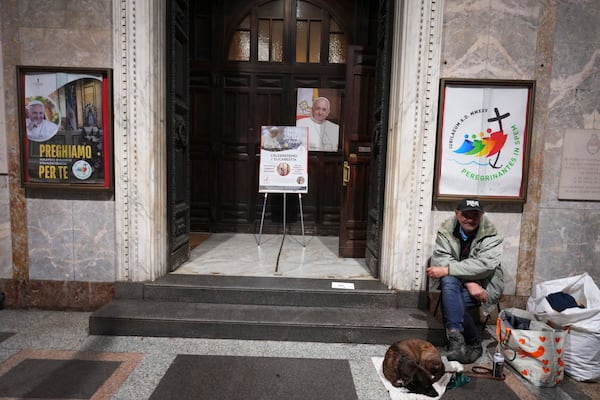 A man sits with his dog outside the Church of the Argentinas before the Pope's Vicar for Rome, Cardinal Baldassare Reina celebrates mass for the health of Pope Francis, Santa Maria Addolorata in Rome, Italy Tuesday, Feb. 25, 2025. (AP Photo/Kirsty Wigglesworth)