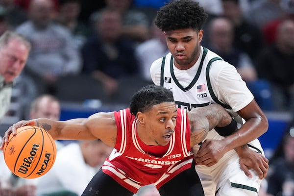 Wisconsin guard Kamari McGee (4) protects the ball from Michigan State guard Jase Richardson (11) during the first half of an NCAA college basketball game in the semifinals of the Big Ten Conference tournament in Indianapolis, Saturday, March 15, 2025. (AP Photo/Michael Conroy)