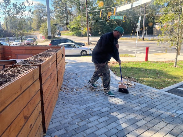 Michael "Killer Mike" Render sweeps the brick-tiled pathway leading into Bankhead Seafood, the restaurant he and fellow star rapper Clifford "T.I." Harris co-own in Atlanta's Westside community, ahead of its opening Nov. 17, 2024. (Mike Jordan/AJC)