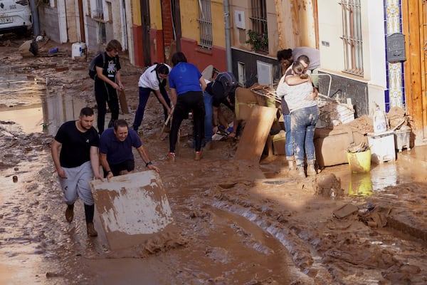 Residents clean their houses affected by floods in Valencia, Spain, Thursday, Oct. 31, 2024. (AP Photo/Alberto Saiz)