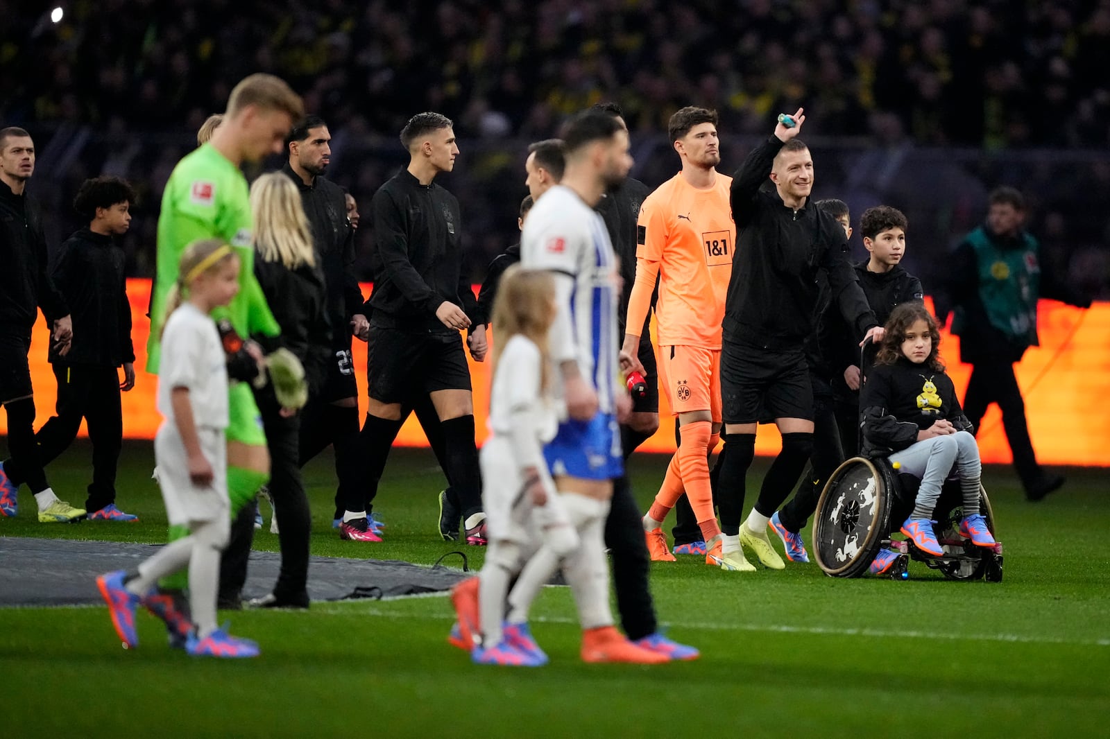 FILE - Dortmund's captain Marco Reus, second right, gestures as he walks into the field with a girl on a wheelchair prior to the start of the German Bundesliga soccer match between Borussia Dortmund and Hertha BSC Berlin at the Westfalenstadion stadium in Dortmund, Germany, Sunday, Feb. 19, 2023. (AP Photo/Martin Meissner, File)