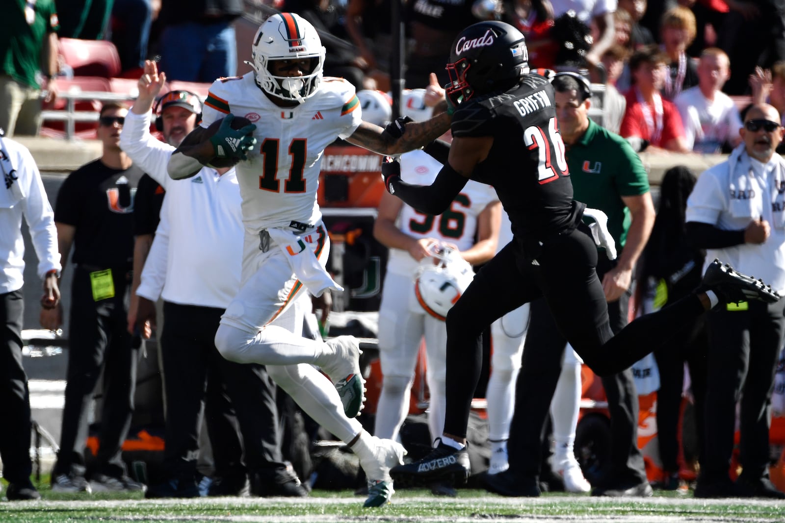 Miami wide receiver Samuel Brown (11) stiff arms Louisville defensive back M.J. Griffin (26) during the second half of an NCAA college football game in Louisville, Ky., Saturday, Oct. 19, 2024. Miami won 52-45. (AP Photo/Timothy D. Easley)