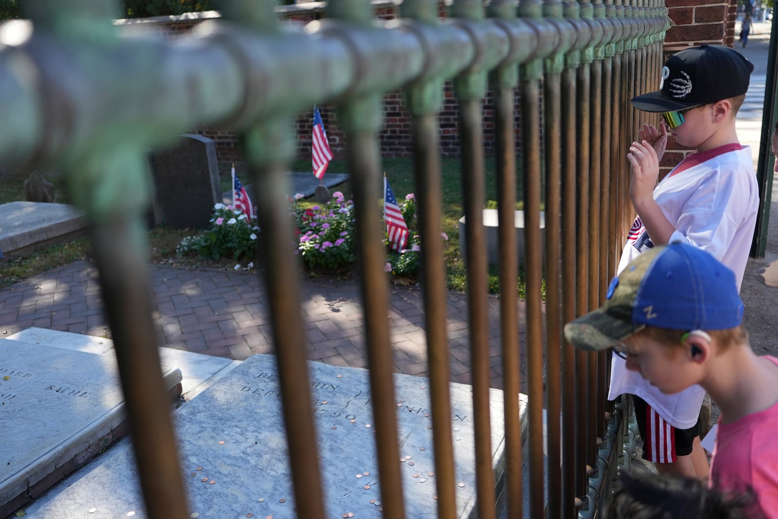 Children look at the penny-covered gravestone of Benjamin Franklin at the Christ Church Burial Ground in Philadelphia on Sunday, Oct. 6, 2024. (AP Photo/Luis Andres Henao)