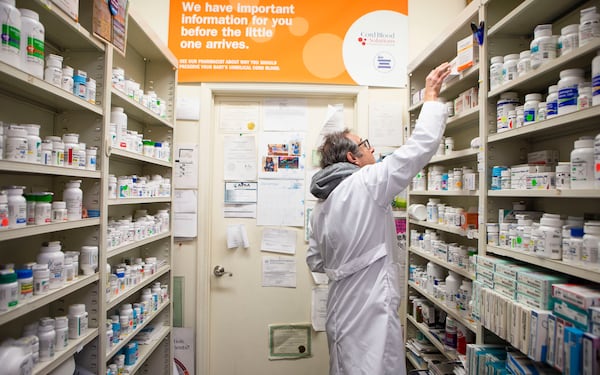 Pharmacist Ira Katz takes down Paxlovid from the shelf of Little Five Points Pharmacy on Friday, December 23, 2022, in Atlanta. Katz dispenses the antiviral pill Paxlovid, for the treatment of COVID-19, to those with a prescription. CHRISTINA MATACOTTA FOR THE ATLANTA JOURNAL-CONSTITUTION.