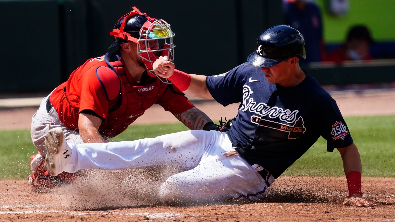 Atlanta Braves' Jake Lamb slides past Boston Red Sox catcher Christian Vazquez to score on a Cristian Pache sacrifice fly in the fifth inning Tuesday, March 23, 2021, at CoolToday Park in North Port, Fla. (John Bazemore/AP)